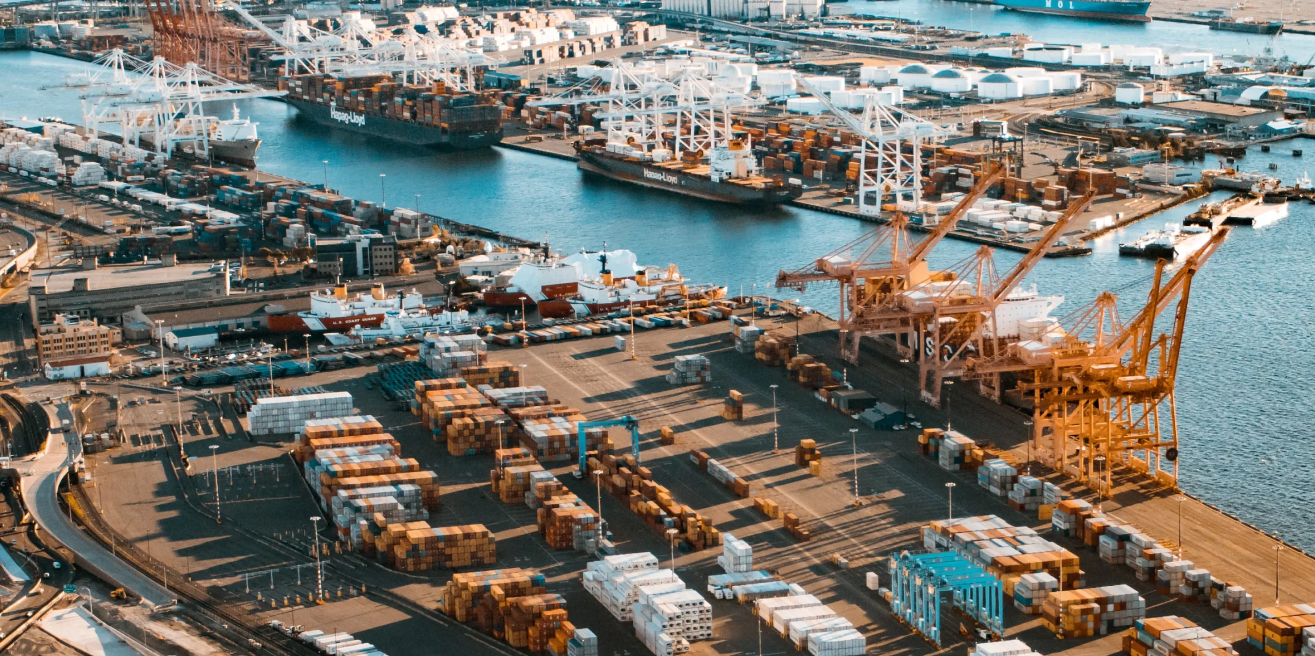 A bustling harbor scene featuring cargo containers and cranes, illustrating the efficiency of maritime operations.