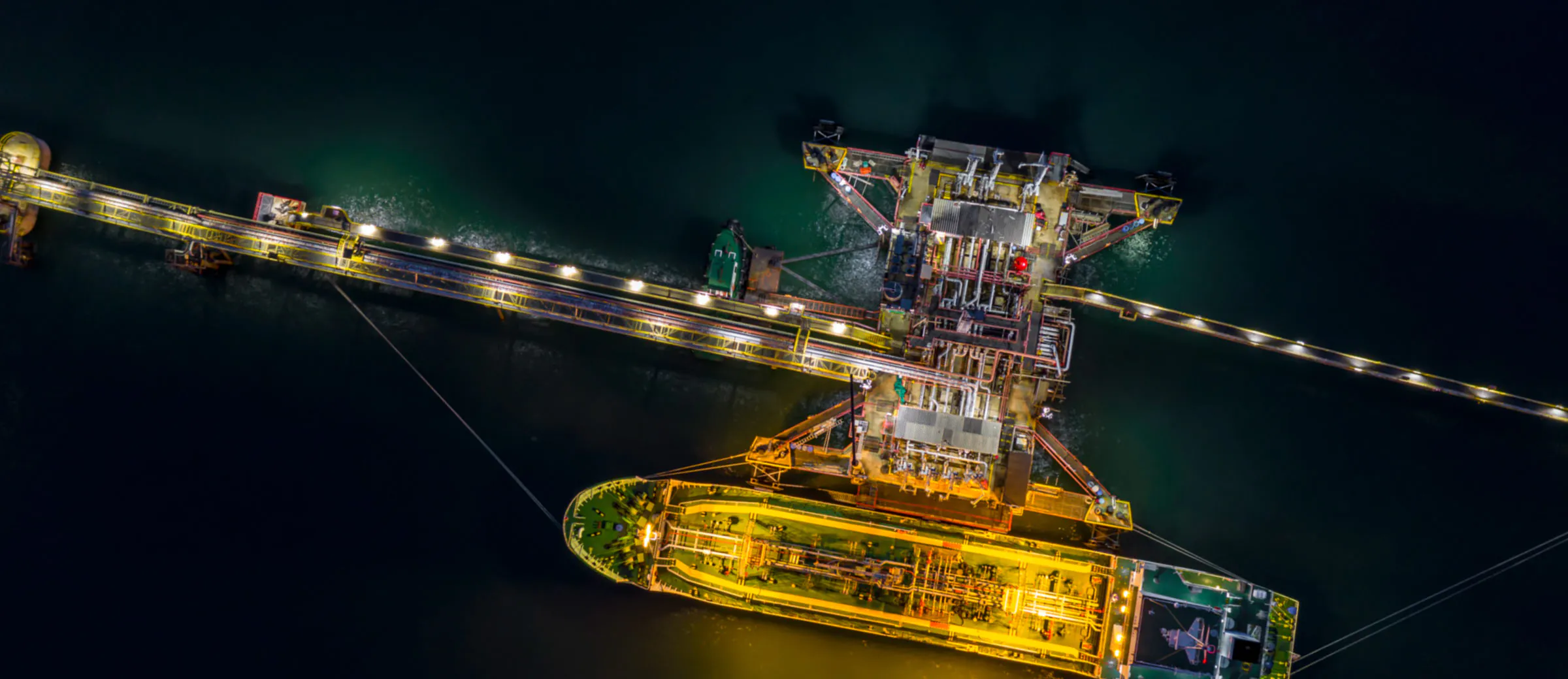 An oil tanker ship illuminated at night.