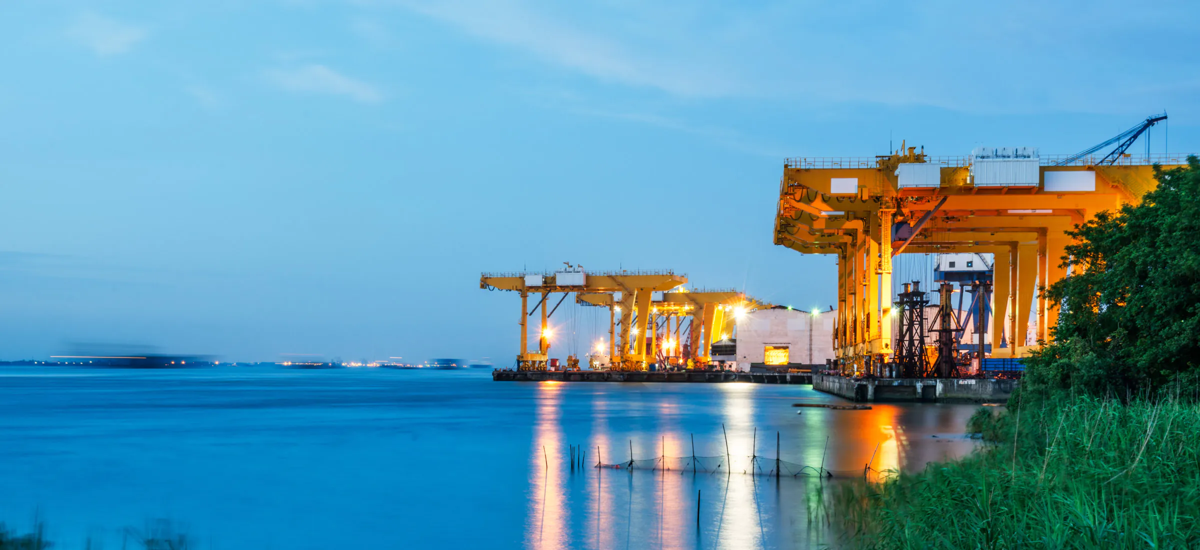 A shipping pier at night featuring mobile cranes